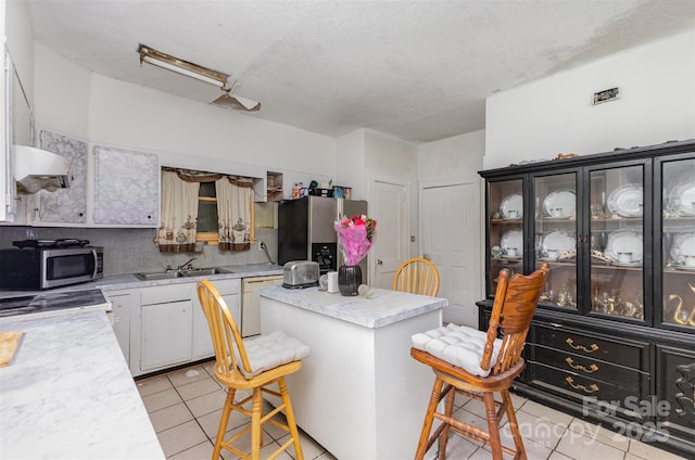 2622 Hemphill St, Charlotte, NC 28208 - kitchen with stainless steel appliances, light tile patterned floors, light countertops, under cabinet range hood, and a textured ceiling
