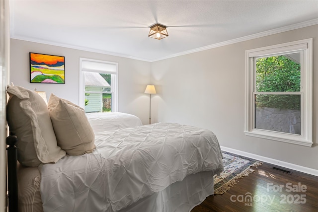 bedroom featuring crown molding, baseboards, visible vents, and wood finished floors