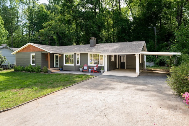 ranch-style home with a front lawn, aphalt driveway, an attached carport, and a chimney