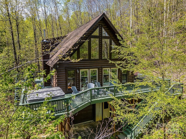 rear view of house featuring log exterior, a wooden deck, and stairs