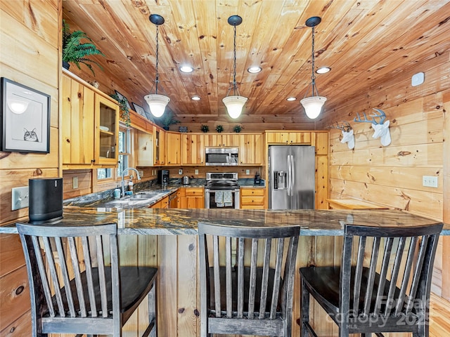 kitchen featuring appliances with stainless steel finishes, a sink, a peninsula, recessed lighting, and glass insert cabinets