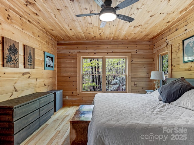 bedroom with wood walls, wooden ceiling, multiple windows, light wood-type flooring, and a ceiling fan