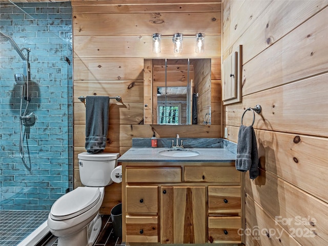 bathroom featuring a shower stall, toilet, vanity, and wooden walls