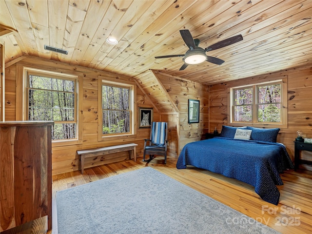 bedroom featuring wood ceiling, wood-type flooring, multiple windows, vaulted ceiling, and wooden walls