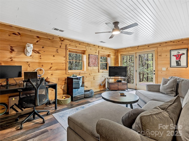 living room featuring healthy amount of natural light, ceiling fan, hardwood / wood-style floors, wooden walls, and a desk