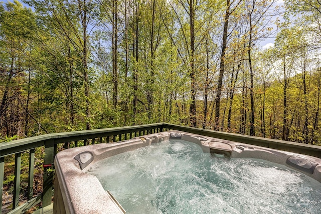 wooden deck with a hot tub and a forest view