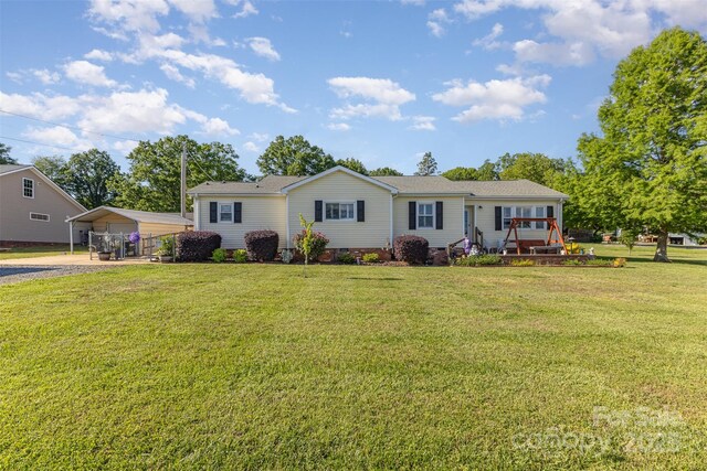 view of front facade featuring a carport, a front lawn, and dirt driveway