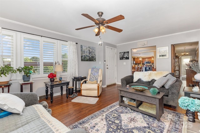 living room with a ceiling fan, wood finished floors, crown molding, baseboards, and a chandelier