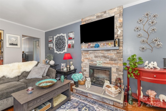 living room featuring crown molding and a stone fireplace