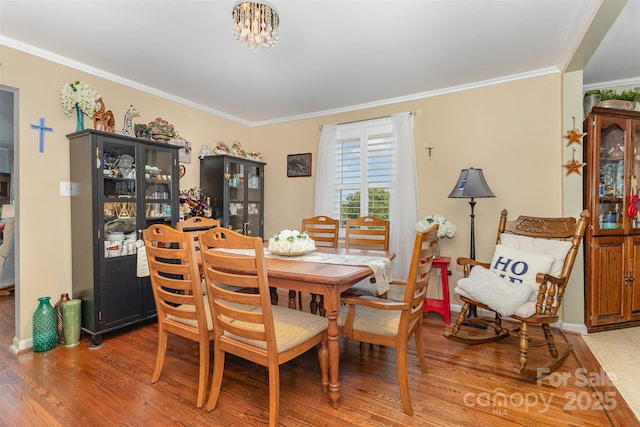 dining room with light wood-style floors, crown molding, baseboards, and a chandelier