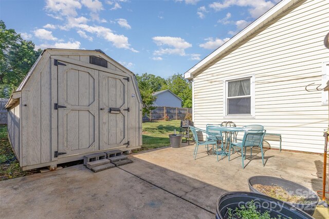 view of patio with a storage unit, a fenced backyard, an outbuilding, and outdoor dining space
