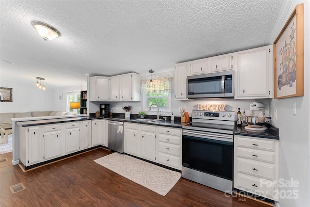 9 Ruby Dr, Hendersonville, NC 28792 - kitchen featuring a textured ceiling, dark countertops, a sink, a peninsula, and stainless steel appliances