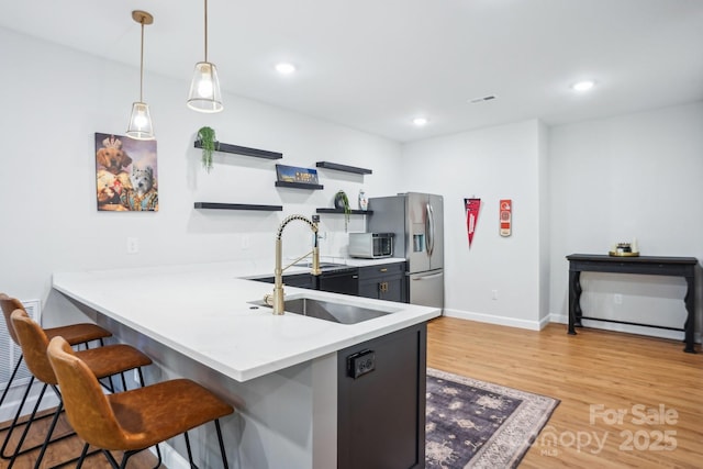 16427 Cozy Cove Rd, Charlotte, NC 28278 - kitchen with open shelves, a kitchen bar, stainless steel refrigerator with ice dispenser, light wood finished floors, and a sink
