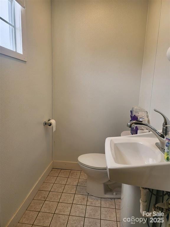 half bath featuring baseboards, tile patterned flooring, and toilet