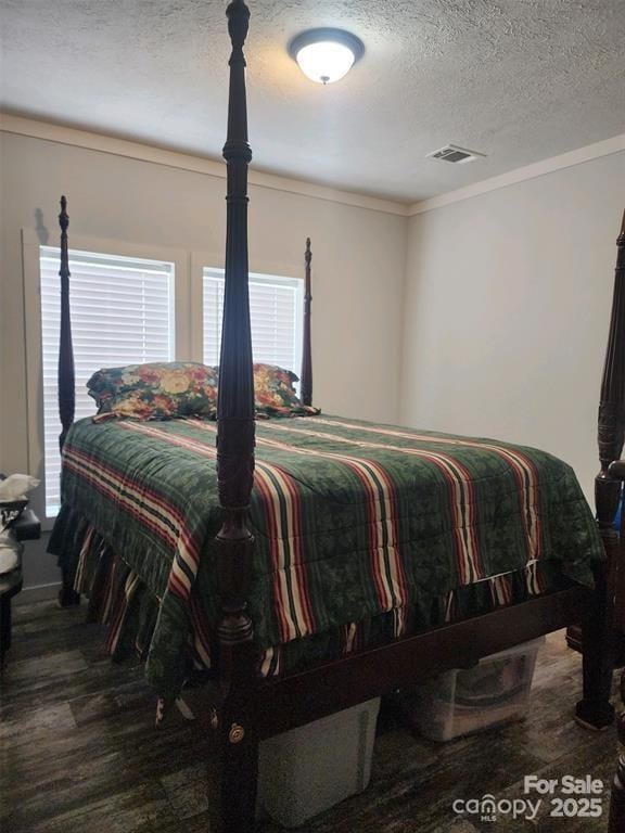 bedroom with crown molding, a textured ceiling, and visible vents
