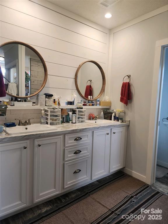 bathroom featuring double vanity, a sink, and baseboards