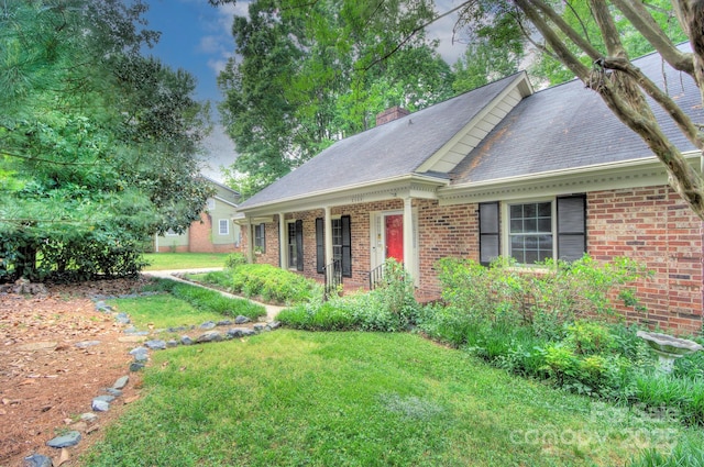 view of side of property featuring a yard, brick siding, a chimney, and a shingled roof
