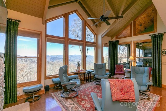 sunroom / solarium featuring wood ceiling, wood finished floors, beam ceiling, and high vaulted ceiling
