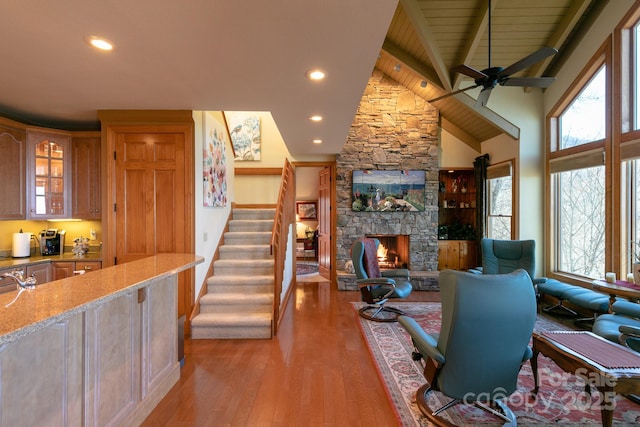 living area with light wood-style floors, a stone fireplace, recessed lighting, stairs, and ceiling fan