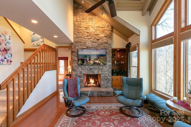 living room with high vaulted ceiling, healthy amount of natural light, a fireplace, wood finished floors, and beamed ceiling