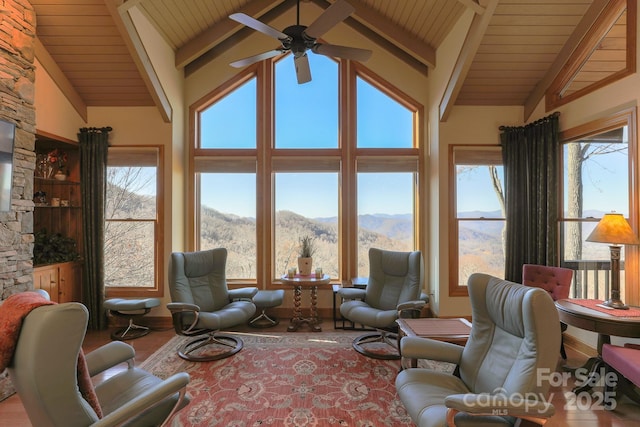 living room with plenty of natural light, a ceiling fan, wood ceiling, a mountain view, and wood finished floors