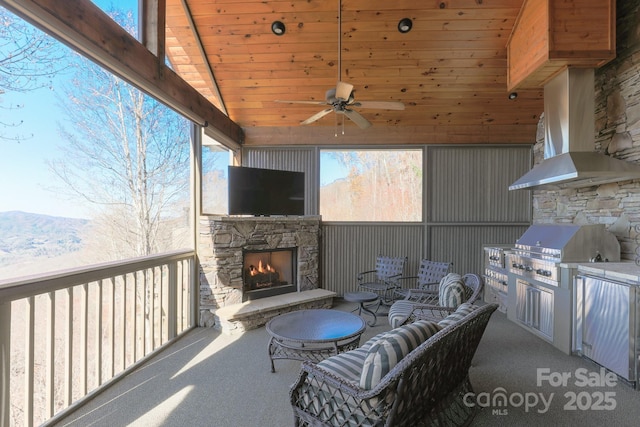 view of patio / terrace featuring exterior kitchen, a ceiling fan, a mountain view, a grill, and an outdoor living space with a fireplace