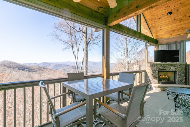 view of patio / terrace featuring an outdoor stone fireplace, outdoor dining area, and a ceiling fan