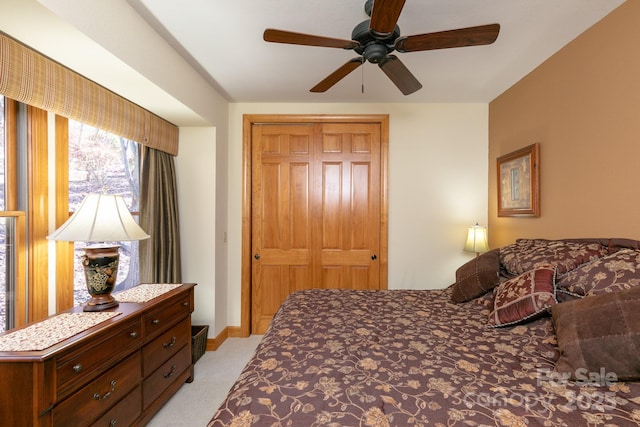 bedroom with light colored carpet, a closet, ceiling fan, and baseboards