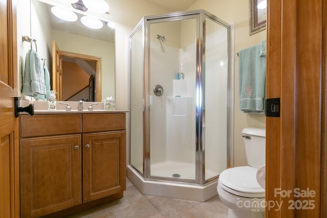 bathroom with tile patterned flooring, toilet, a stall shower, and vanity