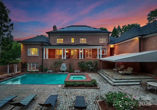 3314 Leamington Ln, Charlotte, NC 28226 - back of property featuring an in-ground hot tub, roof mounted solar panels, brick siding, and a patio area