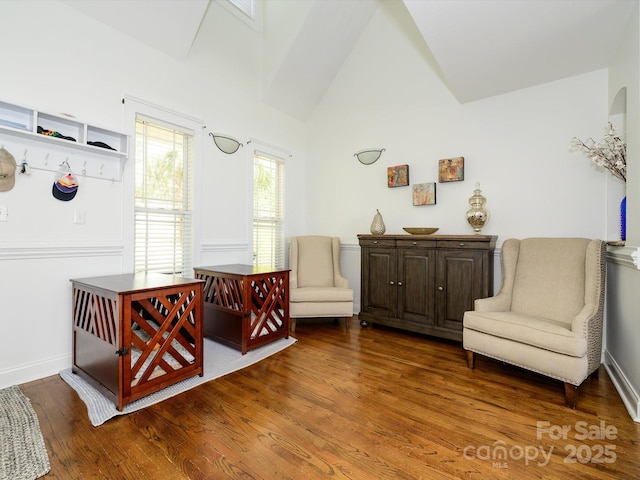 sitting room with baseboards, high vaulted ceiling, and wood finished floors