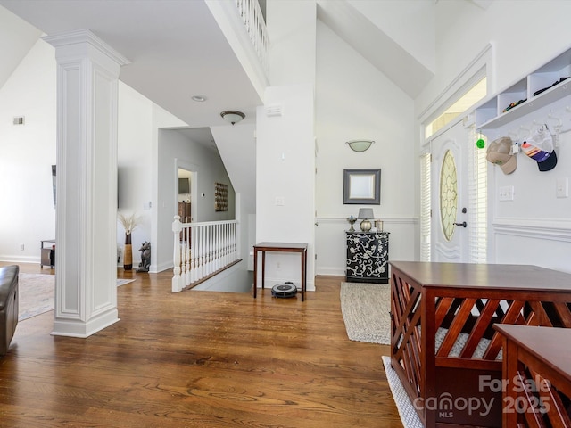 interior space featuring decorative columns, high vaulted ceiling, visible vents, and wood finished floors