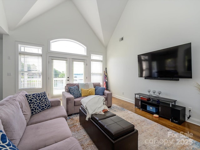living room featuring visible vents, wood finished floors, baseboards, and high vaulted ceiling