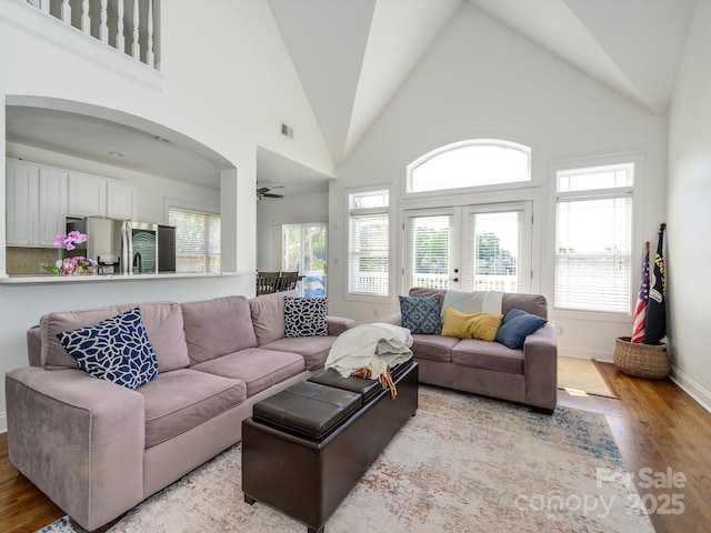 living area featuring a ceiling fan, baseboards, light wood finished floors, visible vents, and arched walkways