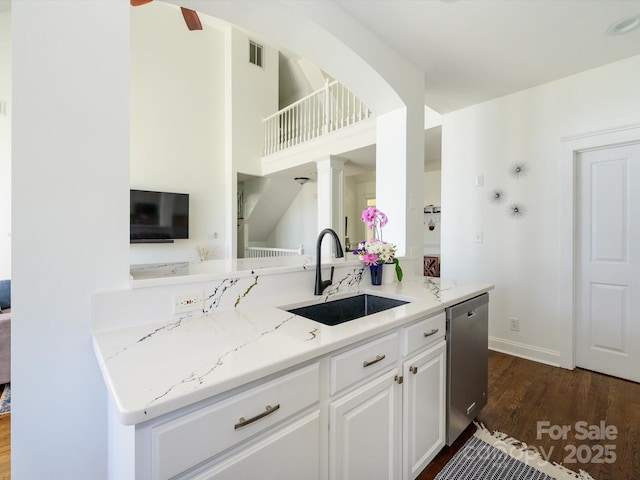 kitchen with a sink, light stone counters, visible vents, dishwasher, and dark wood-style flooring