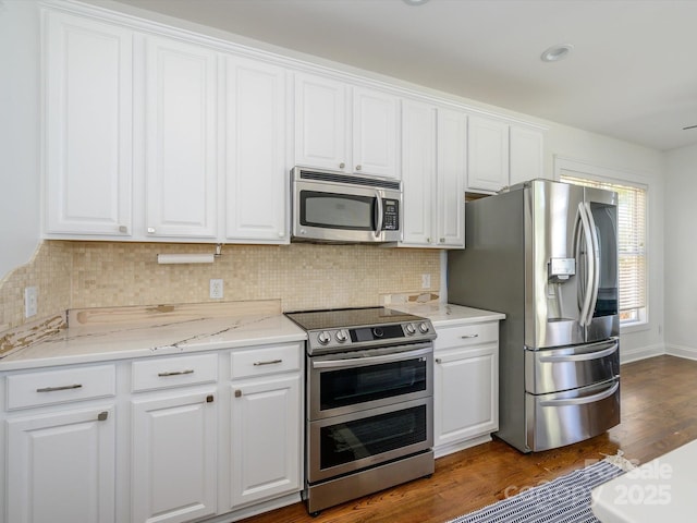 kitchen with backsplash, appliances with stainless steel finishes, dark wood-style flooring, and white cabinetry