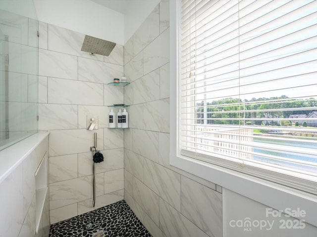 bathroom featuring marble finish floor and a tile shower