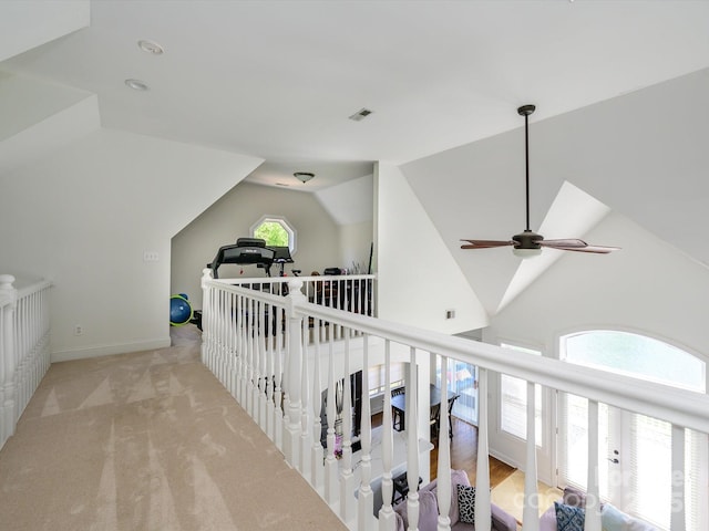 hallway featuring an upstairs landing, visible vents, carpet floors, and vaulted ceiling