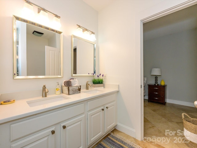 full bathroom with baseboards, double vanity, and a sink