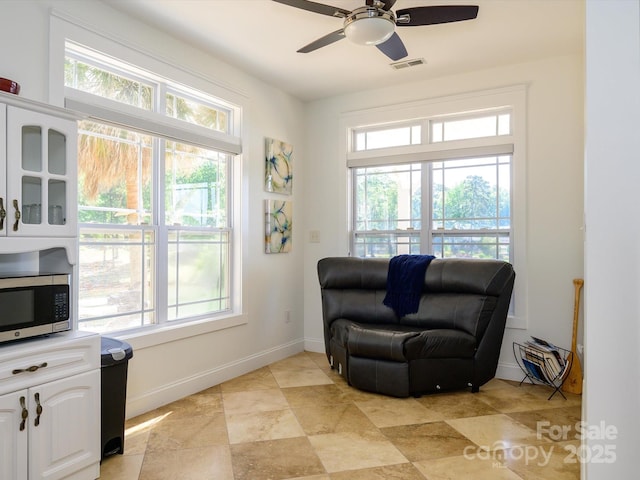 sitting room with baseboards, a ceiling fan, and visible vents