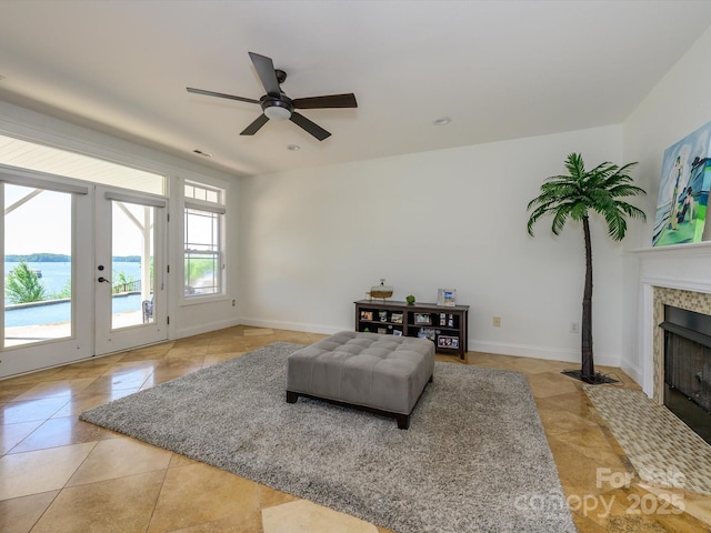 living area with ceiling fan, baseboards, french doors, and a tiled fireplace