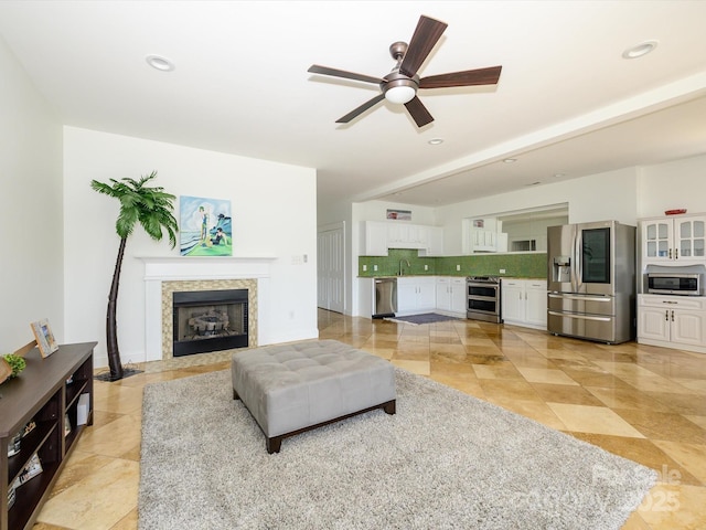 living area featuring a ceiling fan, recessed lighting, light tile patterned floors, and a fireplace with flush hearth