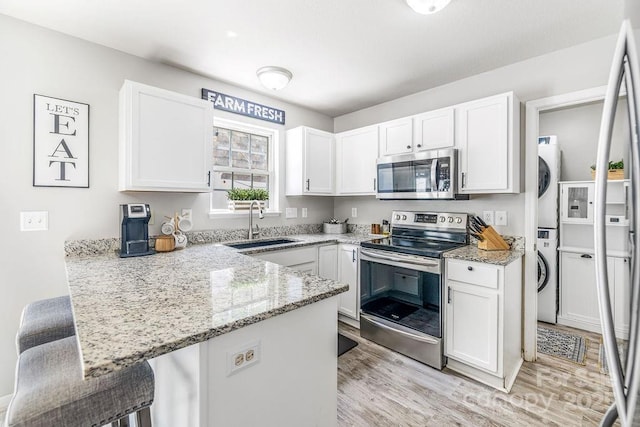 41 Lanceford Cir, Fletcher, NC 28732 - kitchen with stainless steel appliances, estacked washer and dryer, a sink, light wood finished floors, and a peninsula