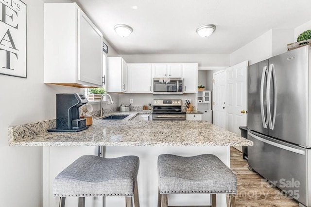 41 Lanceford Cir, Fletcher, NC 28732 - kitchen with appliances with stainless steel finishes, a sink, white cabinets, a peninsula, and light wood-style flooring