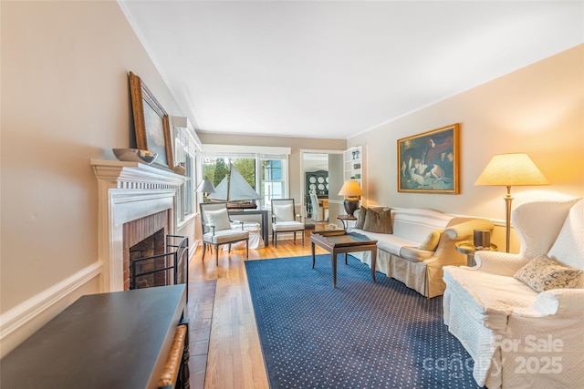 living room featuring a fireplace, crown molding, and hardwood / wood-style flooring