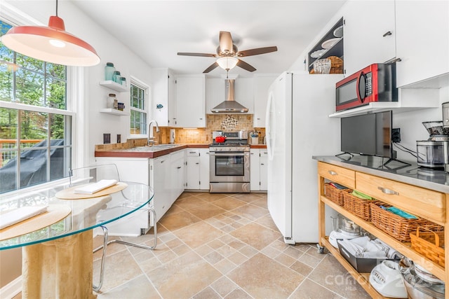 kitchen with a sink, open shelves, white cabinets, white appliances, and wall chimney range hood