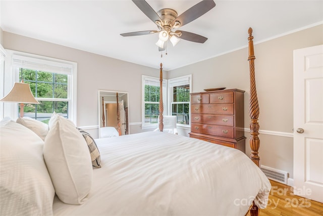 bedroom with light wood finished floors, visible vents, baseboards, and ceiling fan