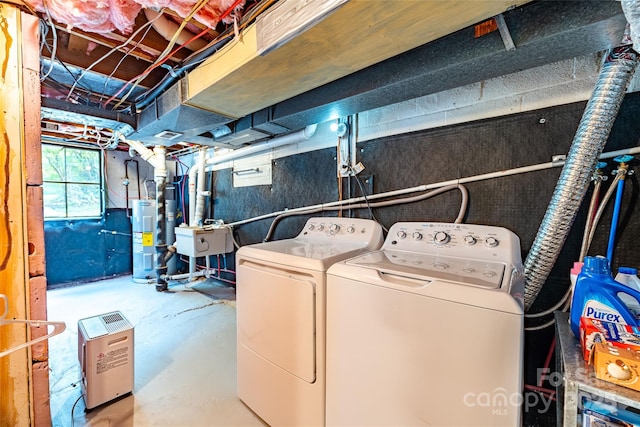 laundry area featuring electric water heater, laundry area, washing machine and dryer, and a sink