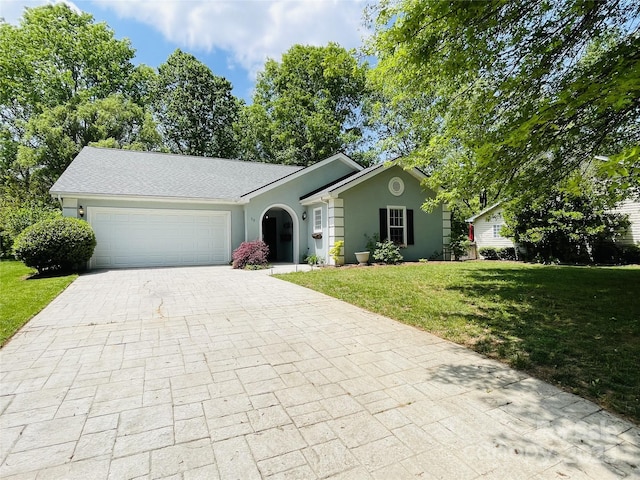 single story home featuring a garage, decorative driveway, stucco siding, and a front yard