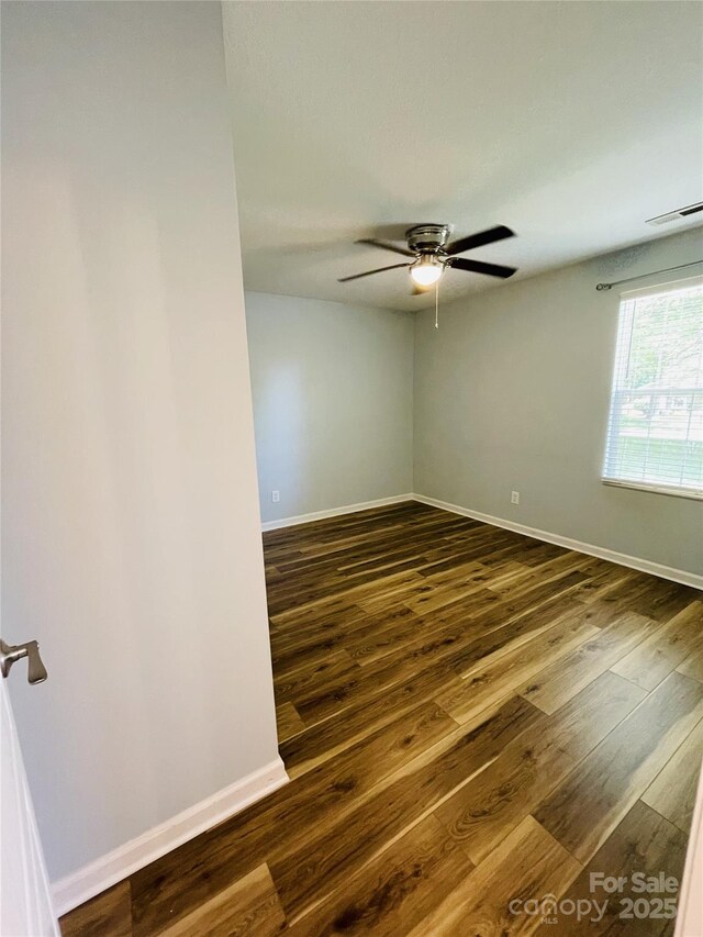 unfurnished room featuring baseboards, ceiling fan, dark wood-type flooring, and visible vents